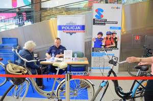 dzielnicowy wypełnia dokumentację dotyczącą znakowania rowerów, a przy nim siedzi właścicielka roweru