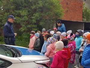 Teren prze komisariatem w Solcu Kujawskim. Dzieci przy radiowozie słuchają policjanta.