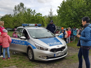 Teren przed komisariatem w Solcu Kujawskim. Dzieci w obecności policjanta oglądają radiowóz.