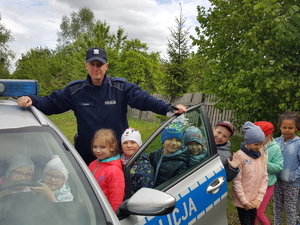 Teren przed komisariatem w Solcu Kujawskim. Dzieci w obecności policjanta wsiadają do radiowozu i pozują do zdjęć.