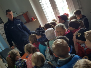 Pomieszczenie komisariatu w Solcu Kujawskim. Dzieci w obecności policjanta zwiedzają jednostkę.