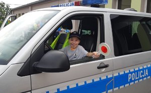 Chłopiec w radiowozie trzyma policyjnego &quot;lizaka&quot; służącego do zatrzymywania kierowców.