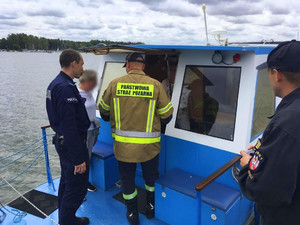 policjant i strażacy kontrolują wyposażenie łodzi