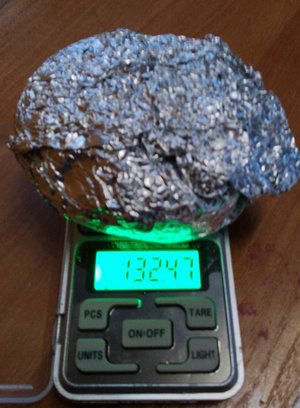 Zawiniątko z folii aluminiowej z zawartością amfetaminy leżące na wadze elektronicznej podczas ważenia.