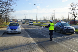 Policjant zatrzymuje do kontroli drogowej nadjeżdżający samochód.