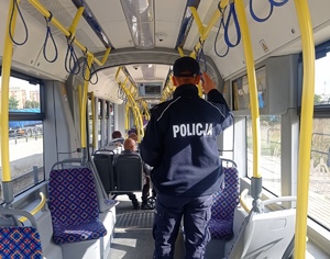 Policjant jadący w tramwaju. W tle pasażerowie.
