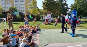Policjant i Polfinek podczas zajęć z dziećmi na terenie przy przedszkolu.