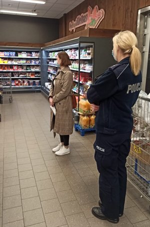 policjantka i pracownik Sanepidu stoją w markecie i obserwują obsługę oraz klientów